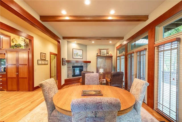 dining area with a fireplace, light wood finished floors, recessed lighting, beamed ceiling, and baseboards