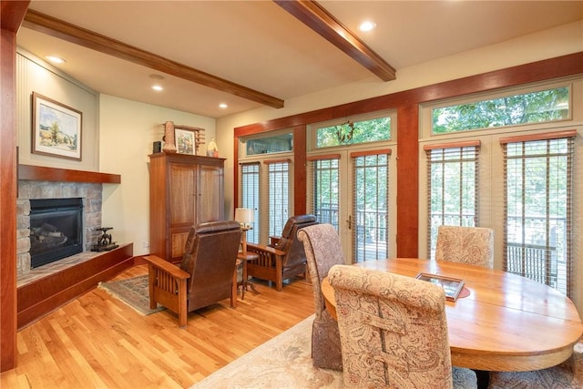 dining area featuring beamed ceiling, recessed lighting, a glass covered fireplace, and light wood-style floors