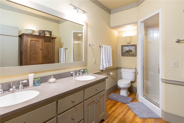 bathroom with wood finished floors, a sink, toilet, and a shower stall