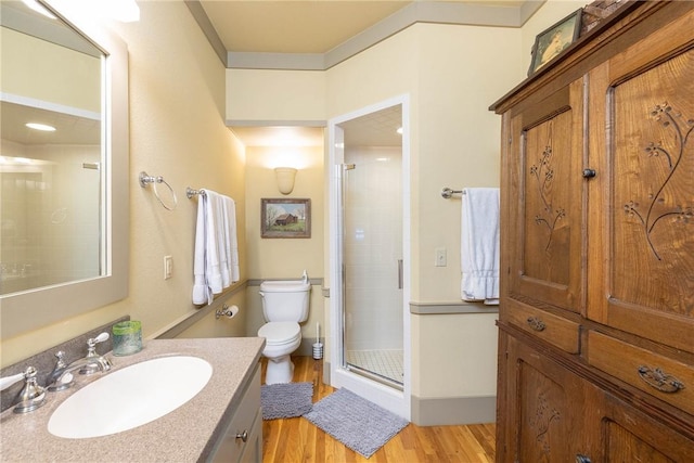 bathroom featuring toilet, a shower stall, wood finished floors, and vanity