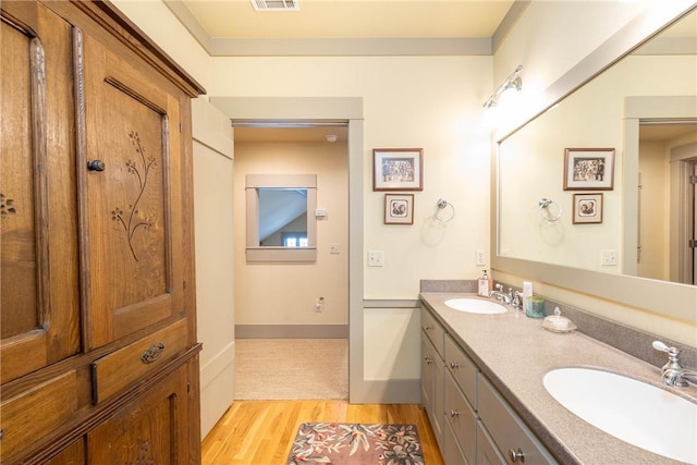 full bathroom featuring double vanity, wood finished floors, a sink, and visible vents