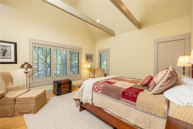 bedroom with multiple windows, high vaulted ceiling, beam ceiling, and wood finished floors