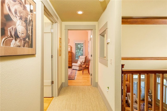 hall featuring a textured ceiling and baseboards