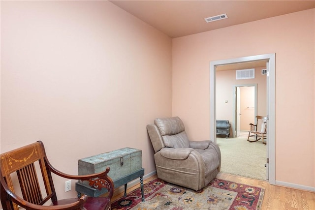 sitting room featuring light wood-type flooring, baseboards, and visible vents