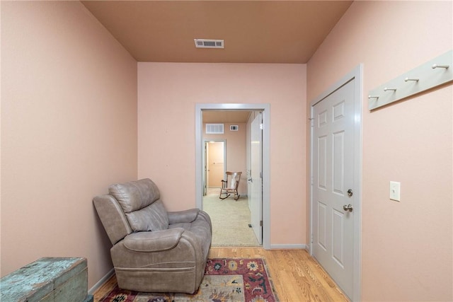 sitting room with light wood finished floors, visible vents, and baseboards