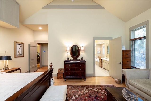 bedroom featuring ensuite bathroom, high vaulted ceiling, and light wood finished floors