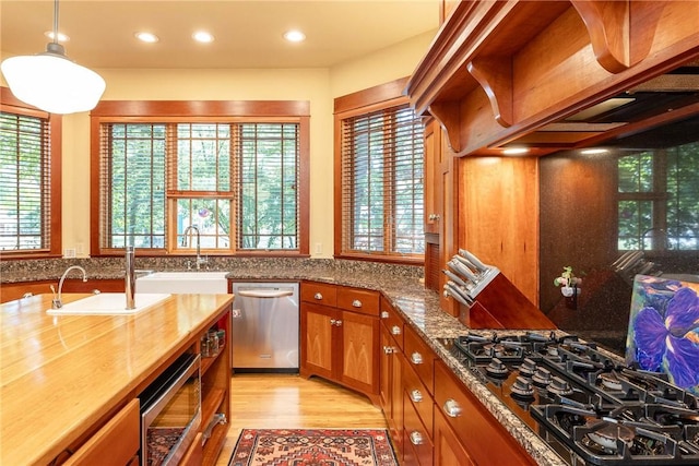 kitchen with stainless steel appliances, brown cabinets, a sink, and light wood finished floors