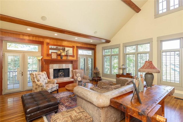 living area featuring plenty of natural light, a fireplace, beamed ceiling, and wood finished floors