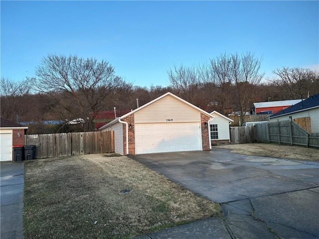 view of side of property featuring aphalt driveway, an attached garage, fence, and brick siding