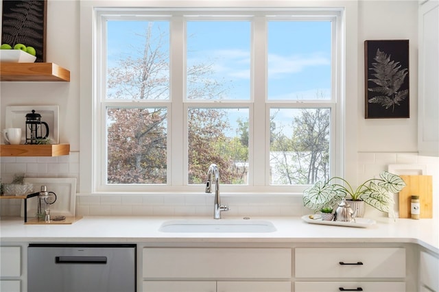 interior space featuring a sink, white cabinets, stainless steel dishwasher, open shelves, and tasteful backsplash