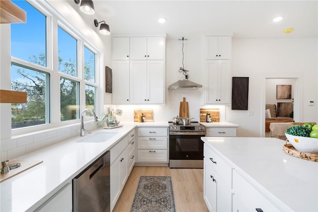 kitchen featuring stainless steel appliances, decorative backsplash, white cabinets, a sink, and light wood-type flooring