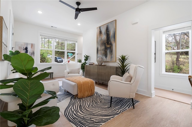 sitting room with baseboards, wood finished floors, a ceiling fan, and a healthy amount of sunlight