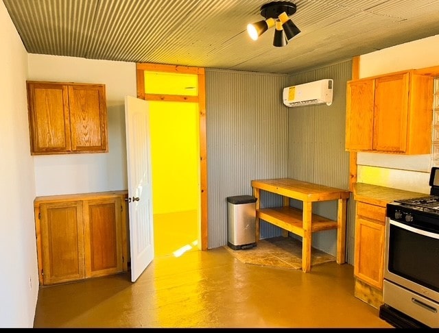 kitchen featuring finished concrete flooring, ceiling fan, brown cabinets, gas stove, and a wall mounted AC