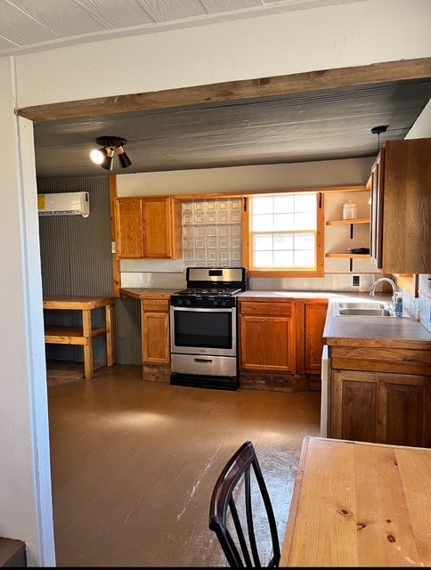 kitchen featuring a wall unit AC, open shelves, a sink, stainless steel gas range oven, and brown cabinets