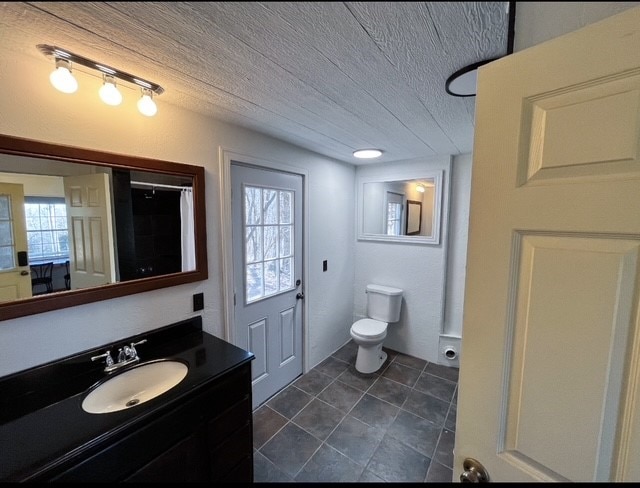 full bath featuring vanity, tile patterned floors, toilet, and a textured ceiling