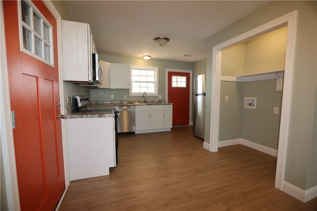 kitchen featuring baseboards, dark wood-style flooring, stainless steel appliances, white cabinetry, and a sink