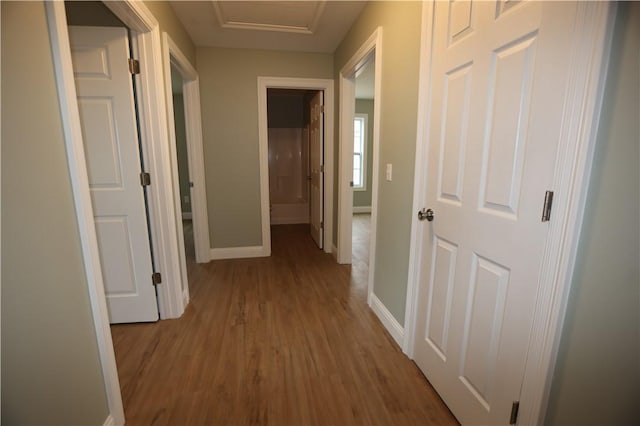 corridor with attic access, baseboards, and wood finished floors