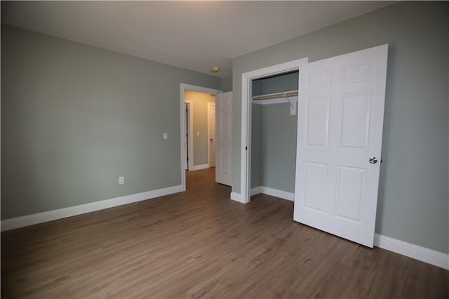 unfurnished bedroom with a closet, wood finished floors, and baseboards