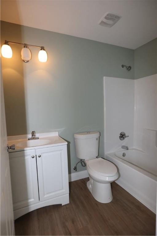 full bathroom featuring visible vents, shower / bathing tub combination, toilet, vanity, and wood finished floors