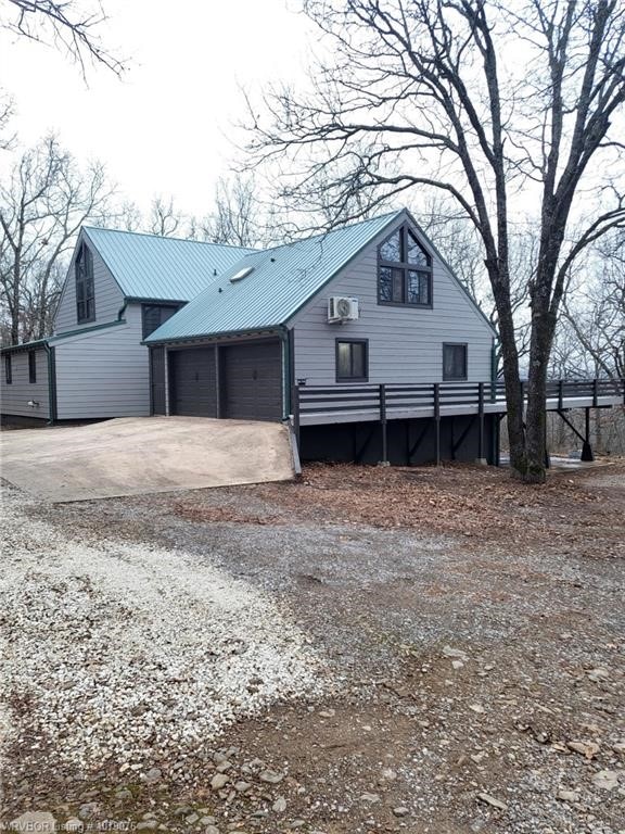 view of front facade with a garage, metal roof, and driveway