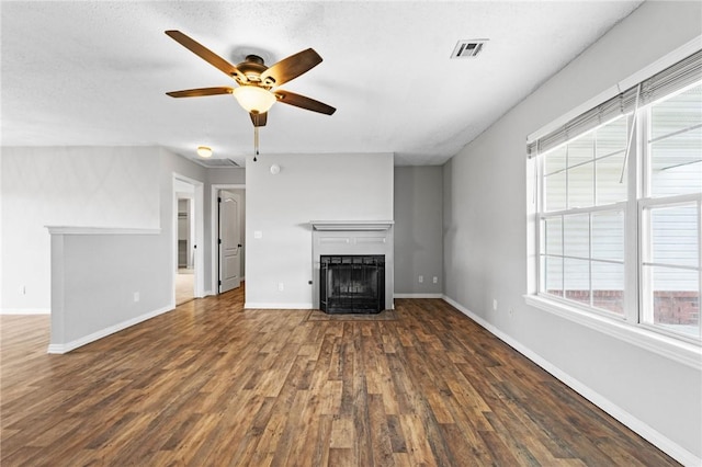 unfurnished living room with a fireplace, wood finished floors, a ceiling fan, visible vents, and baseboards