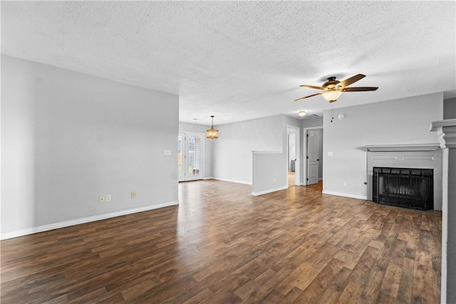 unfurnished living room with a fireplace, a ceiling fan, a textured ceiling, wood finished floors, and baseboards