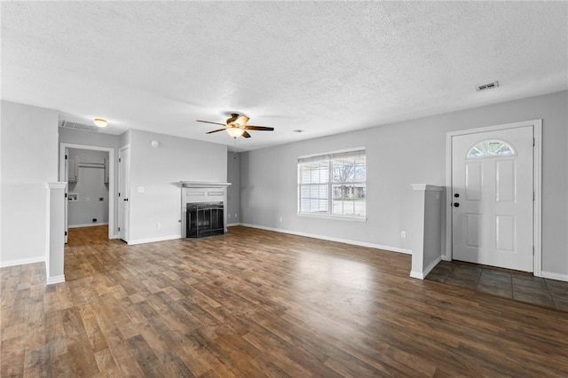 unfurnished living room with a fireplace, visible vents, dark wood-type flooring, a ceiling fan, and a textured ceiling