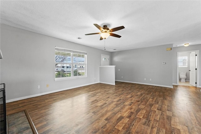 unfurnished living room with ceiling fan, dark wood-type flooring, a textured ceiling, and baseboards