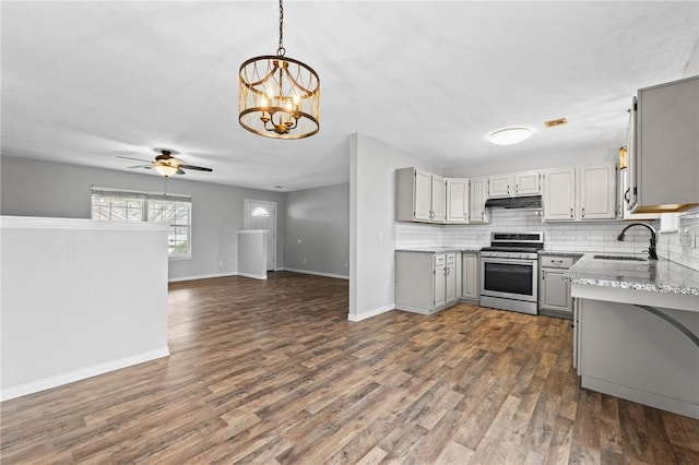 kitchen featuring tasteful backsplash, under cabinet range hood, gray cabinetry, stainless steel range oven, and a sink