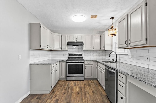 kitchen featuring stainless steel appliances, visible vents, a sink, light stone countertops, and under cabinet range hood