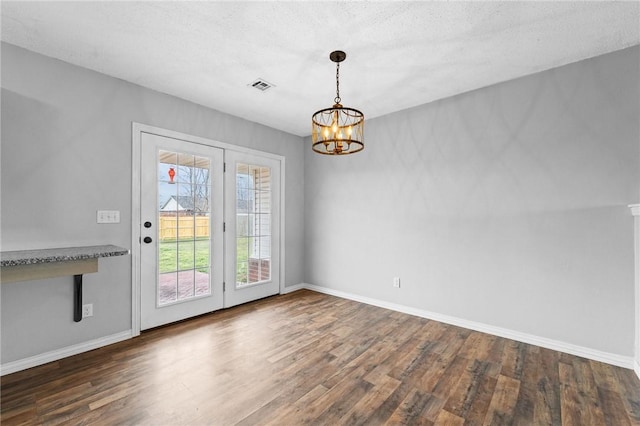 doorway with baseboards, visible vents, dark wood-style flooring, a textured ceiling, and a notable chandelier