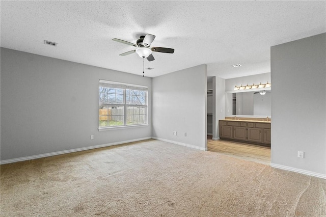 unfurnished bedroom with light carpet, ensuite bath, visible vents, and baseboards