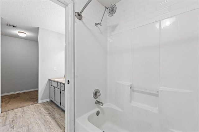 full bathroom featuring visible vents, wood finished floors, bathtub / shower combination, a textured ceiling, and vanity