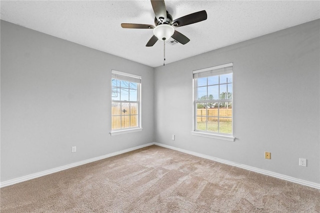 empty room with a textured ceiling, a ceiling fan, visible vents, baseboards, and carpet