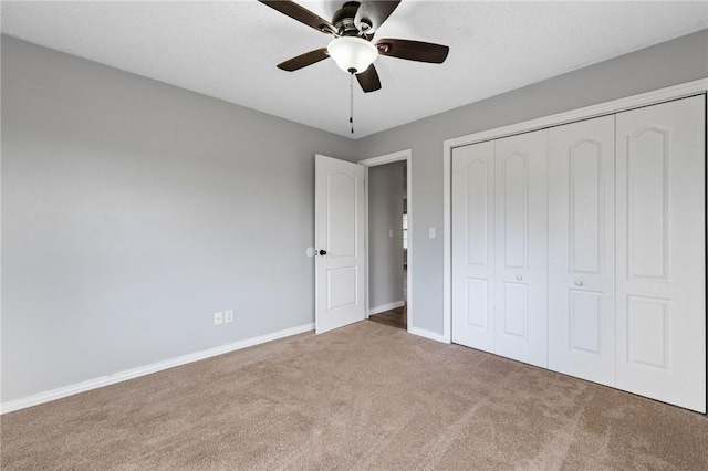 unfurnished bedroom with carpet floors, a closet, baseboards, and a ceiling fan