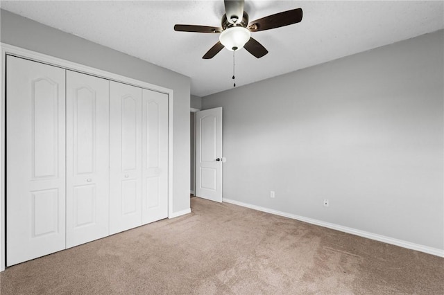 unfurnished bedroom featuring ceiling fan, a closet, baseboards, and carpet flooring