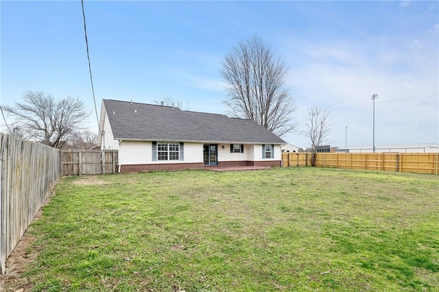 back of house featuring brick siding, a lawn, a patio area, and a fenced backyard