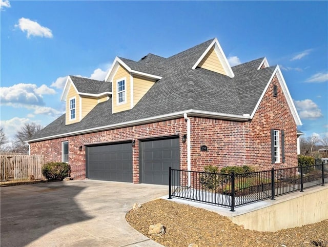 view of side of home featuring an attached garage, brick siding, fence, driveway, and roof with shingles