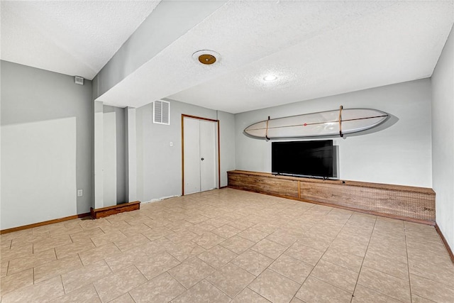 interior space featuring visible vents, a textured ceiling, and baseboards