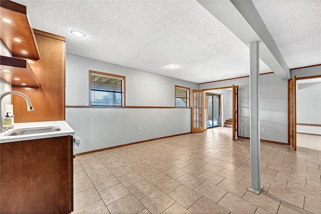 interior space with a textured ceiling, baseboards, light countertops, and a sink