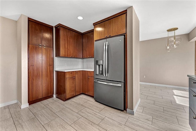 kitchen with stainless steel fridge, baseboards, decorative backsplash, and light countertops