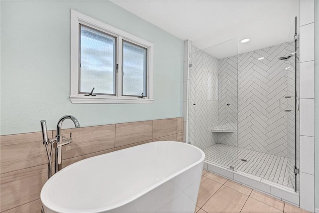 bathroom featuring a stall shower, a soaking tub, and tile walls