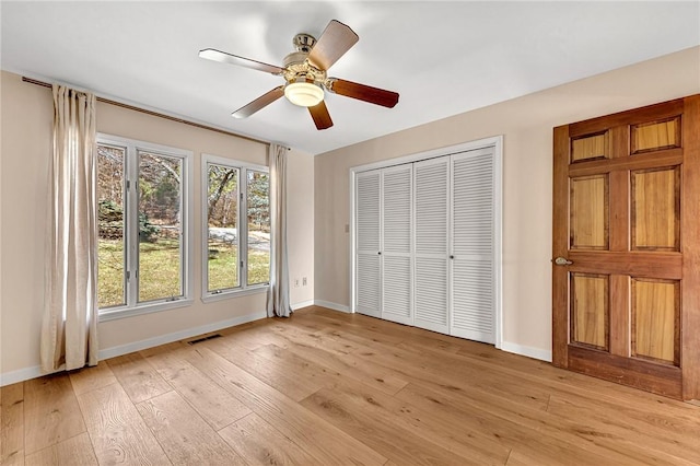 unfurnished bedroom featuring baseboards, a closet, visible vents, and light wood-style floors