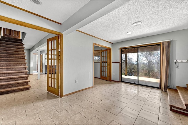 empty room with light tile patterned floors, baseboards, stairs, a textured ceiling, and french doors