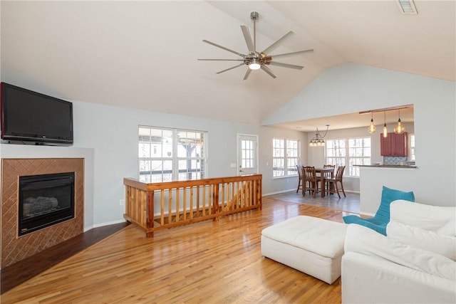 33 Rountree Dr, Bella Vista, AR 72715 - living area featuring light wood-type flooring, a ceiling fan, a fireplace with flush hearth, baseboards, and high vaulted ceiling