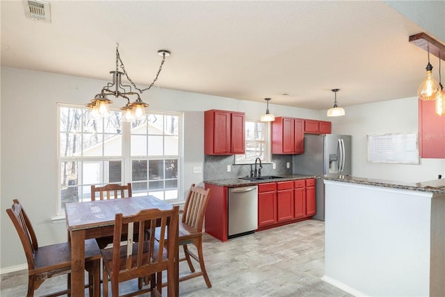 33 Rountree Dr, Bella Vista, AR 72715 - kitchen featuring stainless steel appliances, a sink, decorative backsplash, reddish brown cabinets, and a chandelier