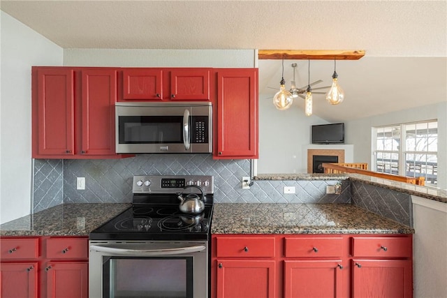 33 Rountree Dr, Bella Vista, AR 72715 - kitchen featuring appliances with stainless steel finishes, decorative backsplash, a fireplace, vaulted ceiling, and dark countertops