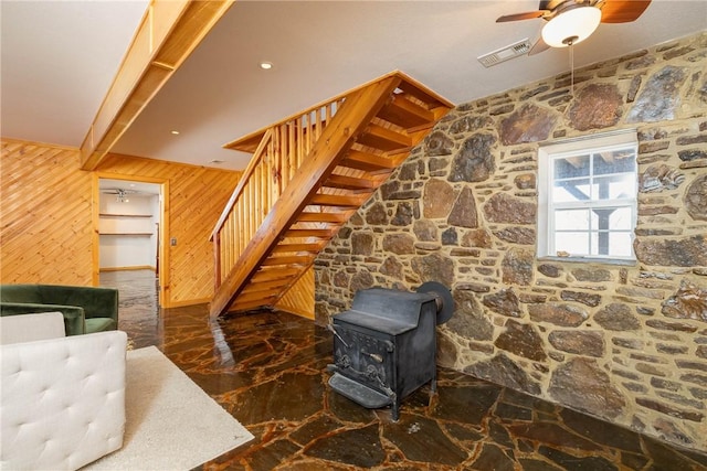 33 Rountree Dr, Bella Vista, AR 72715 - living room featuring wooden walls, a wood stove, stairway, a ceiling fan, and marble tiled flooring