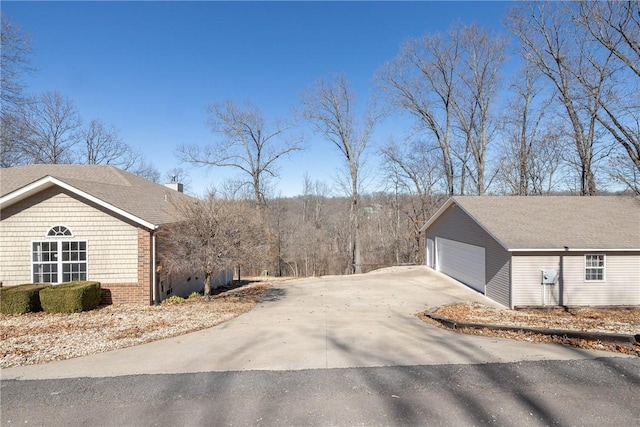 33 Rountree Dr, Bella Vista, AR 72715 - view of property exterior with an outdoor structure, a chimney, a detached garage, brick siding, and driveway