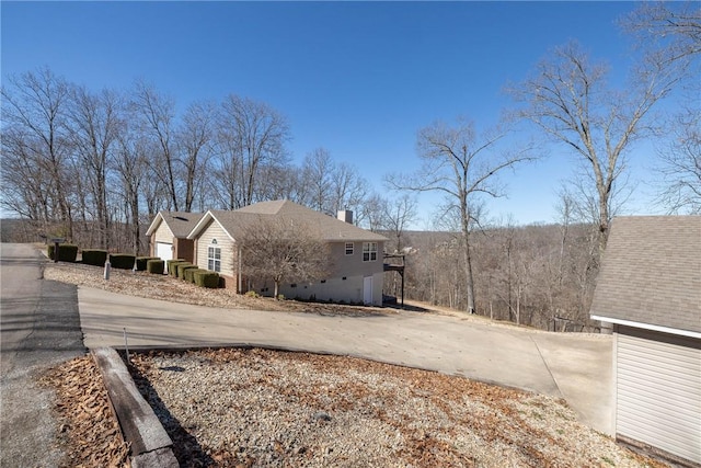 33 Rountree Dr, Bella Vista, AR 72715 - view of home's exterior with a chimney and concrete driveway